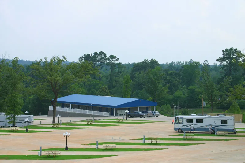 Concrete RV sites and the blue-roofed clubhouse with pine woods behind