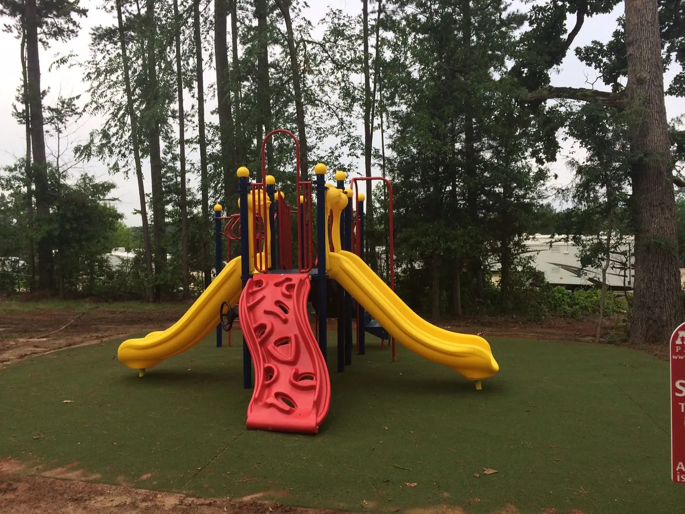 The playground, with slides and a climbing frame under the pines